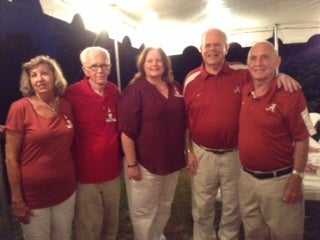 Group of people sitting at table outside under a tent.