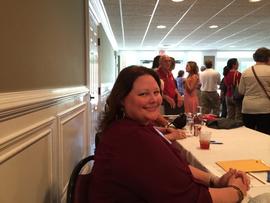 Lady in crimson top sitting at a table.