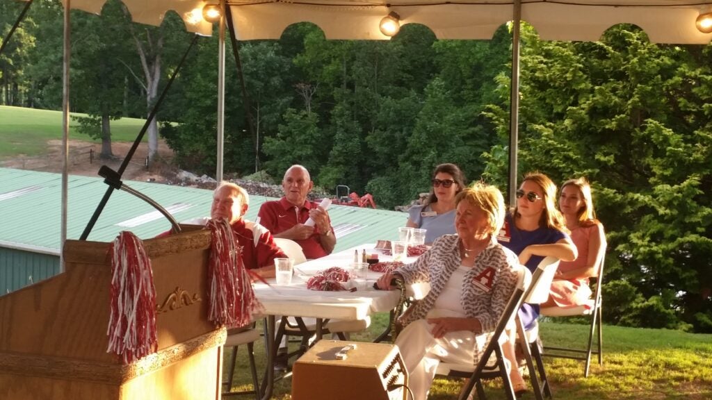 Group of people sitting at table outside under a tent.