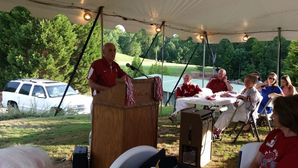Man standing behind podium outside.