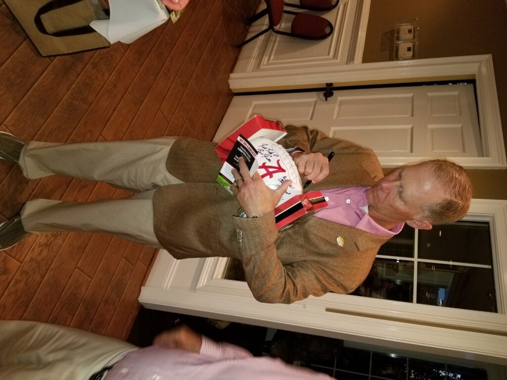 Man in Beige Jacket standing in room with white door in background.