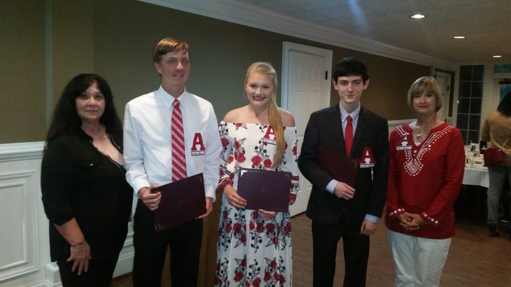Three people standing in room with dim light.
