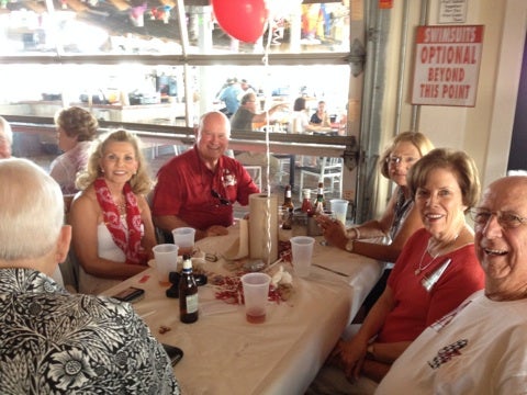 Group of people sitting at table with red balloon and in front of window.