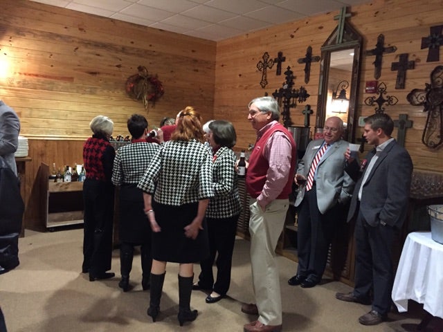 Group of people standing in room with brown walls.