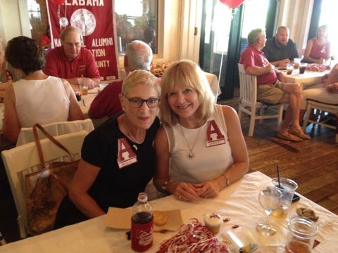 Group of people sitting at table with red banner in background.