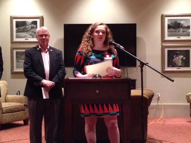 Man in dark suit and girl in red/blue dress standing behind podium.