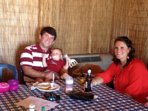 Group of people sitting at table with black/white table cloth and brown walls.