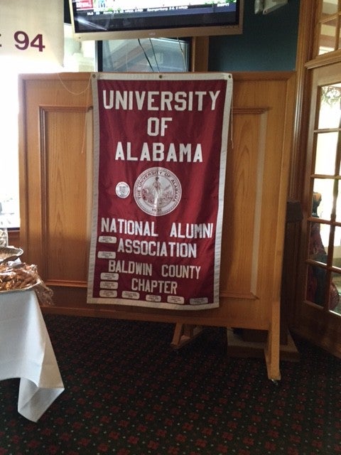 Red and white Univeristy of Alabama banner on brown wall.