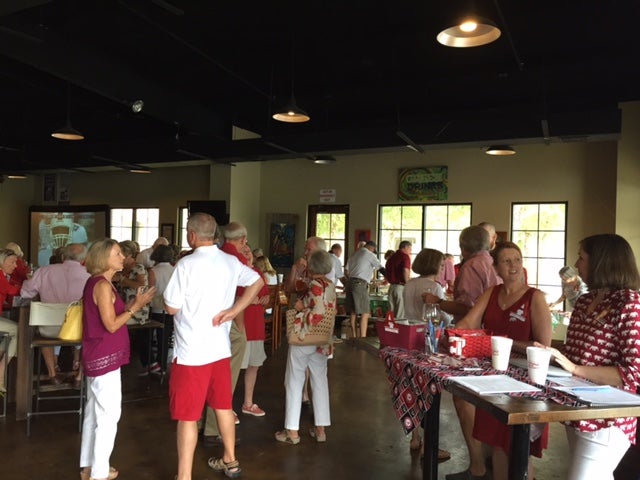 Group of people standing in room with windows in background.