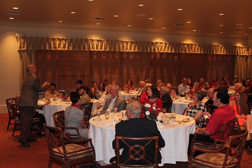 Group of people sitting at tables in dim light room.