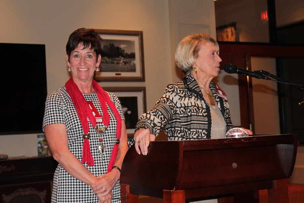 Two ladies standing behind podium in dim light room.