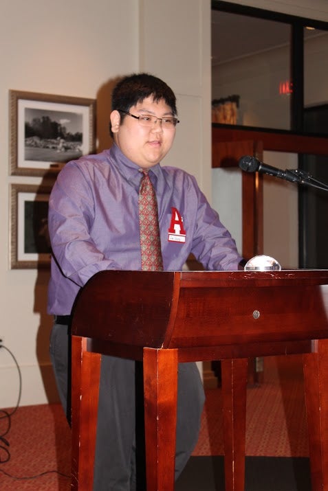 Man standing behind podium in dim light room.