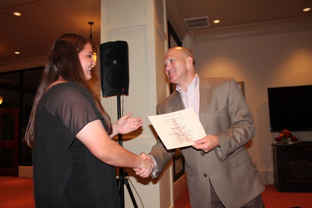 Dean Chuck Karr presenting a certificate to student in dark top.