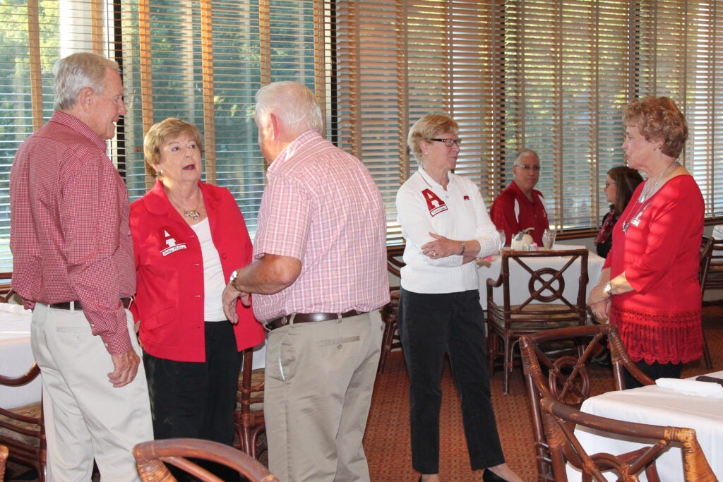 Group of people standing in room in front of window.