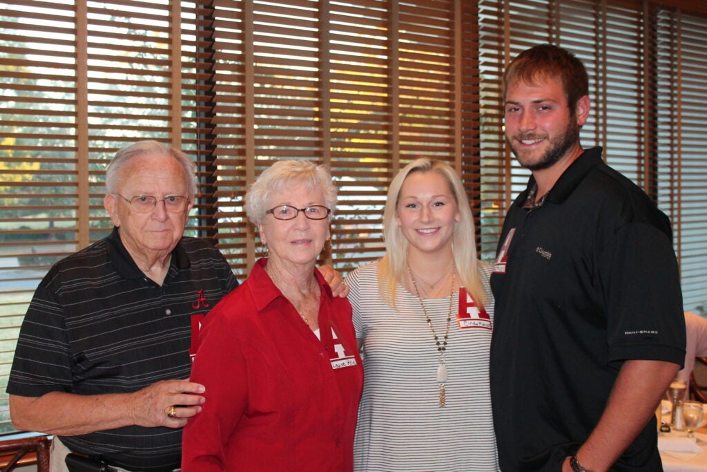 Group of people standing in front of window with brown shades.