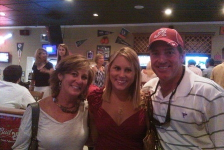 Three people standing in dim light room.