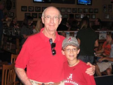 Two people in red shirts standing in dim light room.