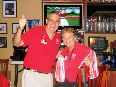 two people dressed in red standing in front of TV Screen.