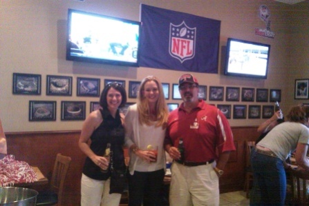 Three people standing in front of TV Screen.