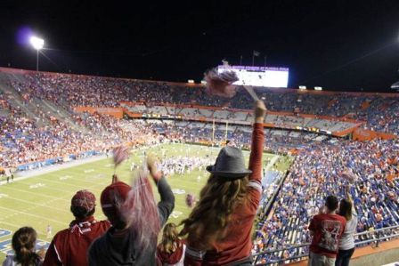 Fans standing in stadium at football game.