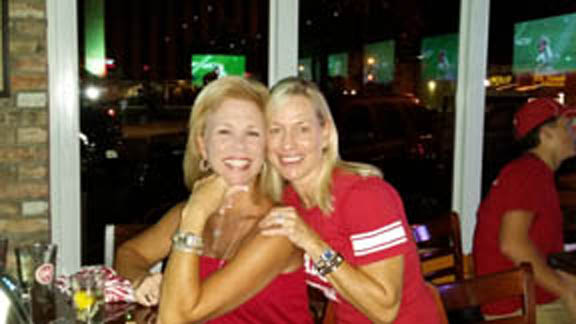 Two ladies in Red standing in dim light room.