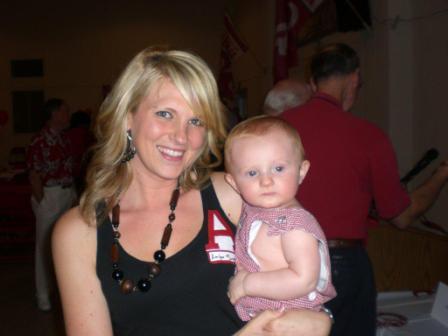 A lady holding a baby outside.