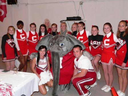 Group of people with Big Al standing in room with white wall.