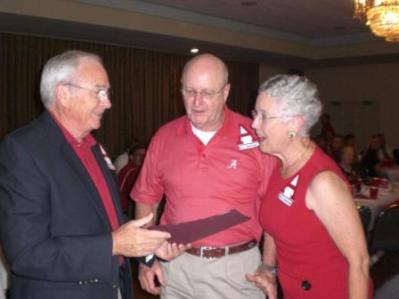 Three people standing in room with dark wall.