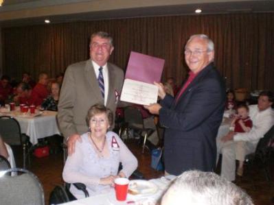 Two people standing and one person n wheelchair in room with curtain in background.