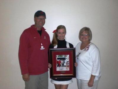 Three people standing and one holding a framed picture.