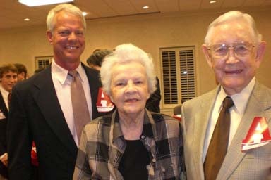 Group of people standing in room with beige wall.
