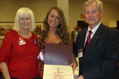 Group of people standing in room and one person holding a certificate.