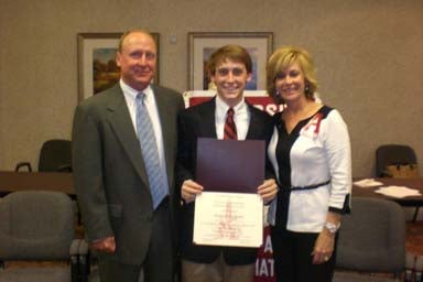 Three people standing in room and one holding a certificate.
