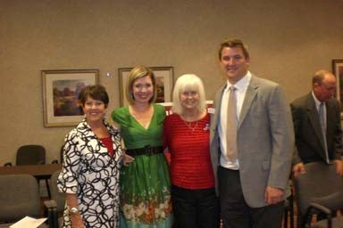 Group of people standing in room with beige wall.