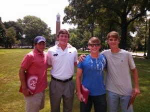 Group of four students stand outside in front of Denny Chimes