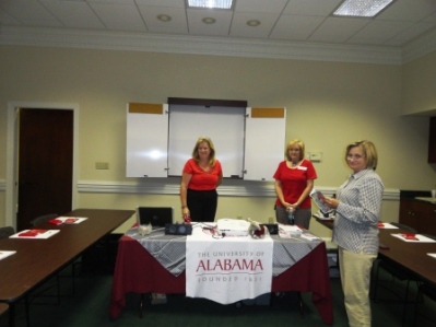 Three people standing behind table with white banner.