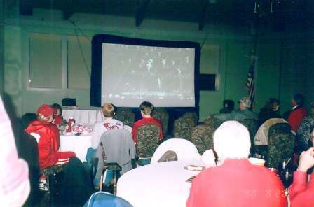 Group of people in room with screen in background.