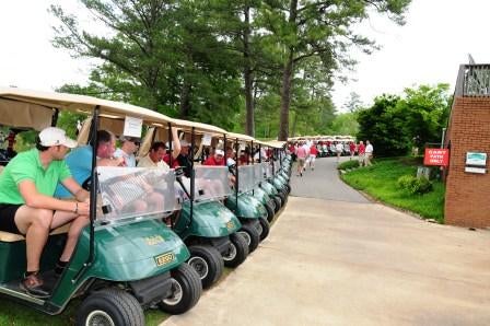 Green golf carts with trees in background.