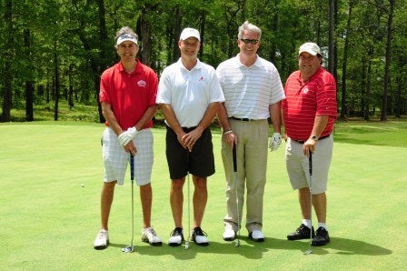 Group of men standing outside on golf course.