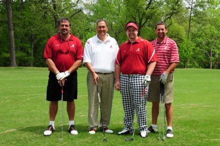 Group of men standing outside on golf course.