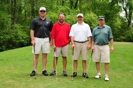 Group of men standing outside on golf course.