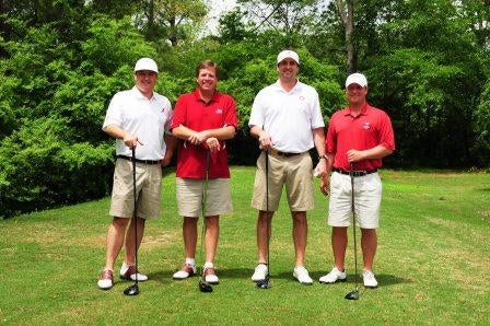 Group of men standing outside on golf course.