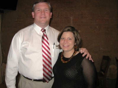 Man in white shirt and red and white tie and lady in black dress.