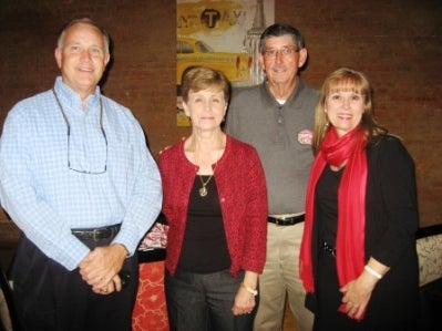 Group of people standing in room with dark walls in background.