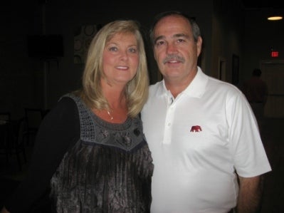 Lady in black top and man in white shirt standing in dark room.