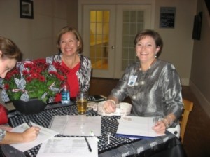 Two ladies sitting at table with glass door in background.