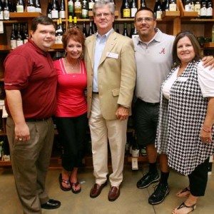 Group of people standing in front of wine display.