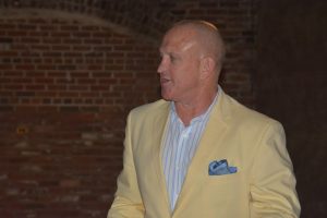 Man in yellow coat standing in front of brick wall