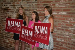 three students holding red Bama Bound signs