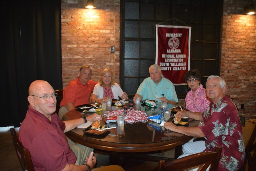 Group of people sitting at table in dim light room.